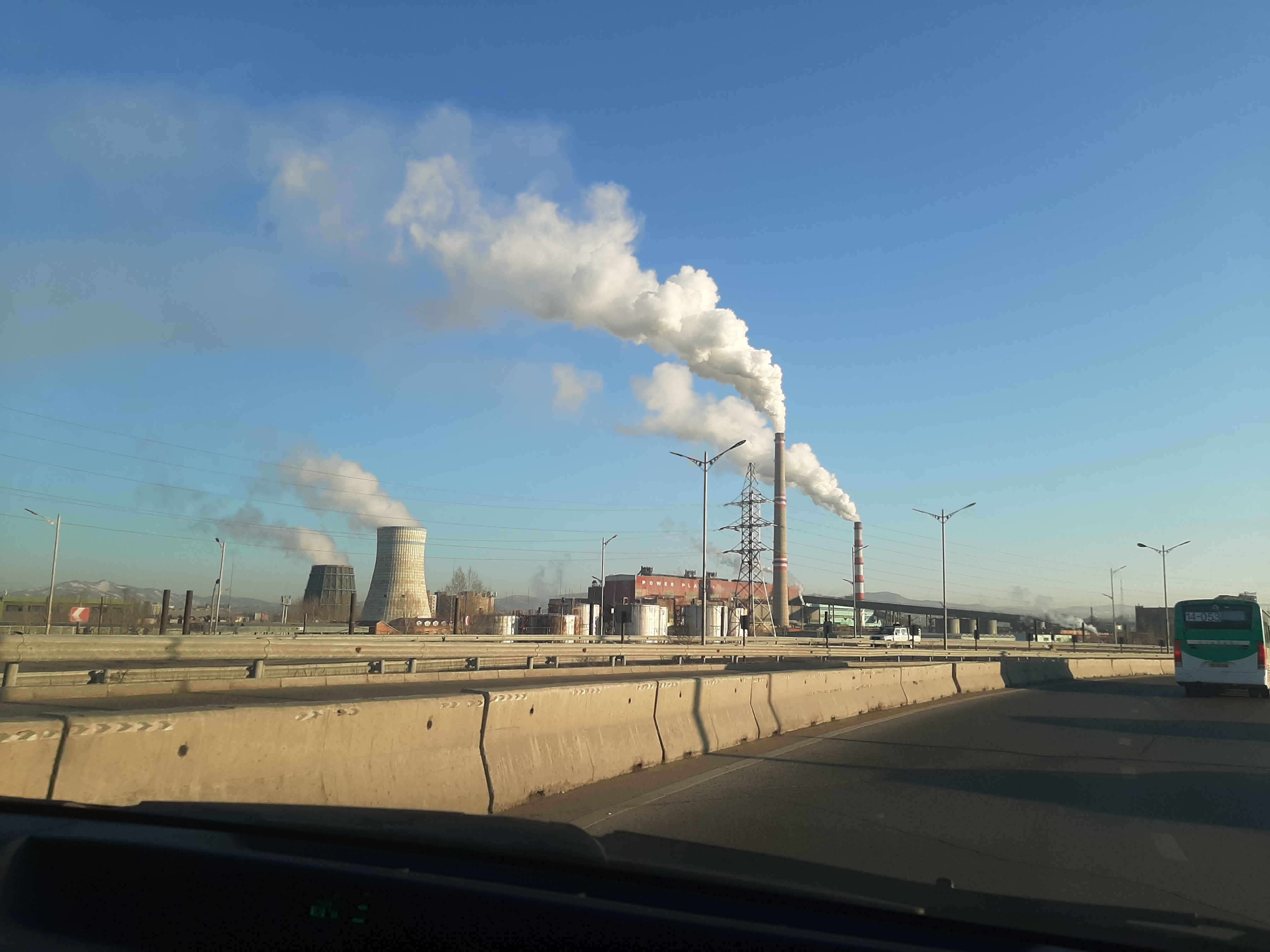 Smoking chimneys in a concrete landscape under a blue sky.