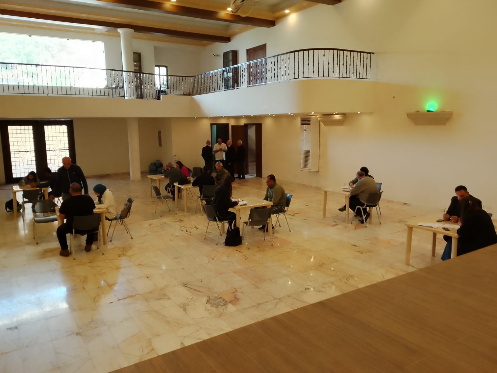 Big hall with people sitting on scattered tables conducting interviews.