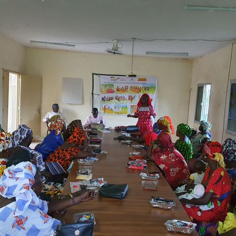 A group of predominantly female participants in colourful clothes learning about their land rights.