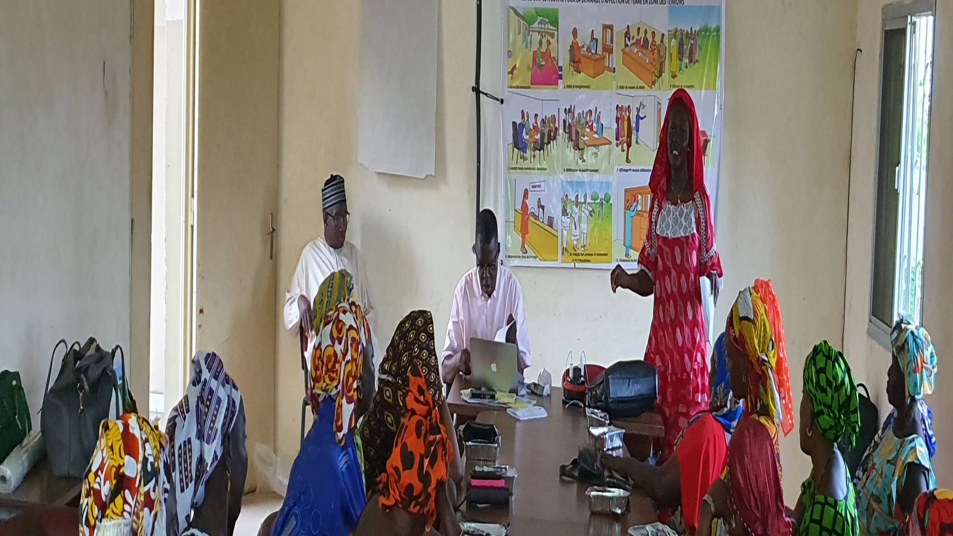 A group of predominantly female participants in colourful clothes learning about their land rights.