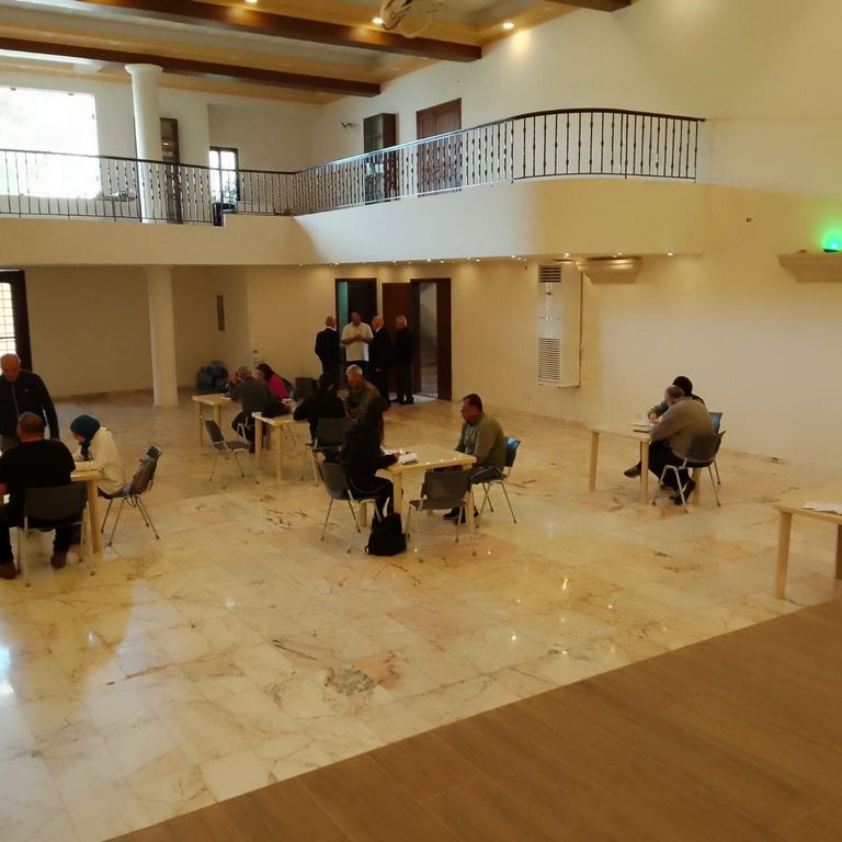Big hall with people sitting on scattered tables conducting interviews.