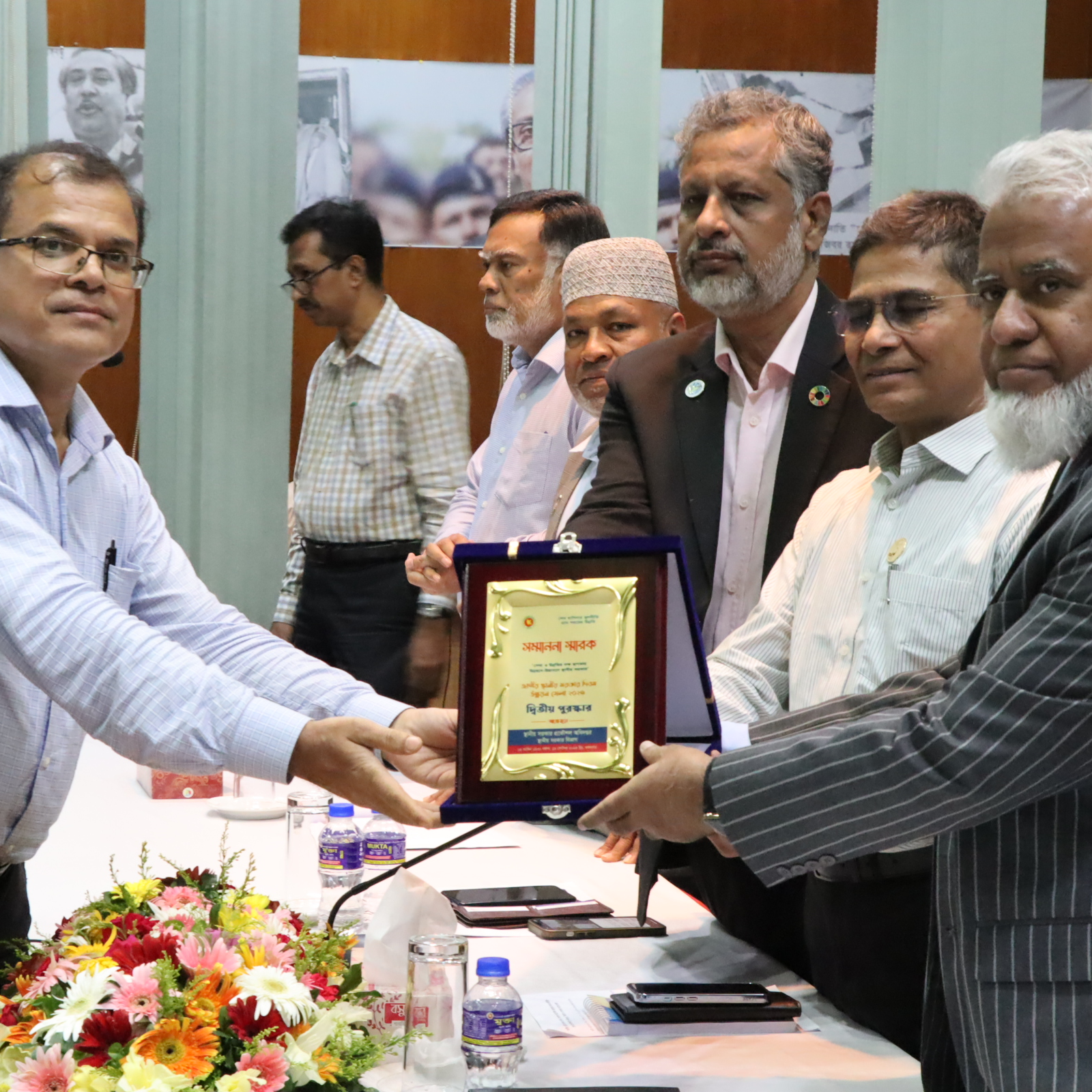 A group of men from the National Local Government Day of Bangladesh is handing over a certificate to the CReLIC team leader.
