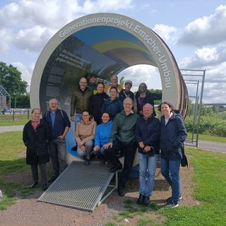 A group of people in front of the memorial site "Generationenprojekt Emscher-Umbau"
