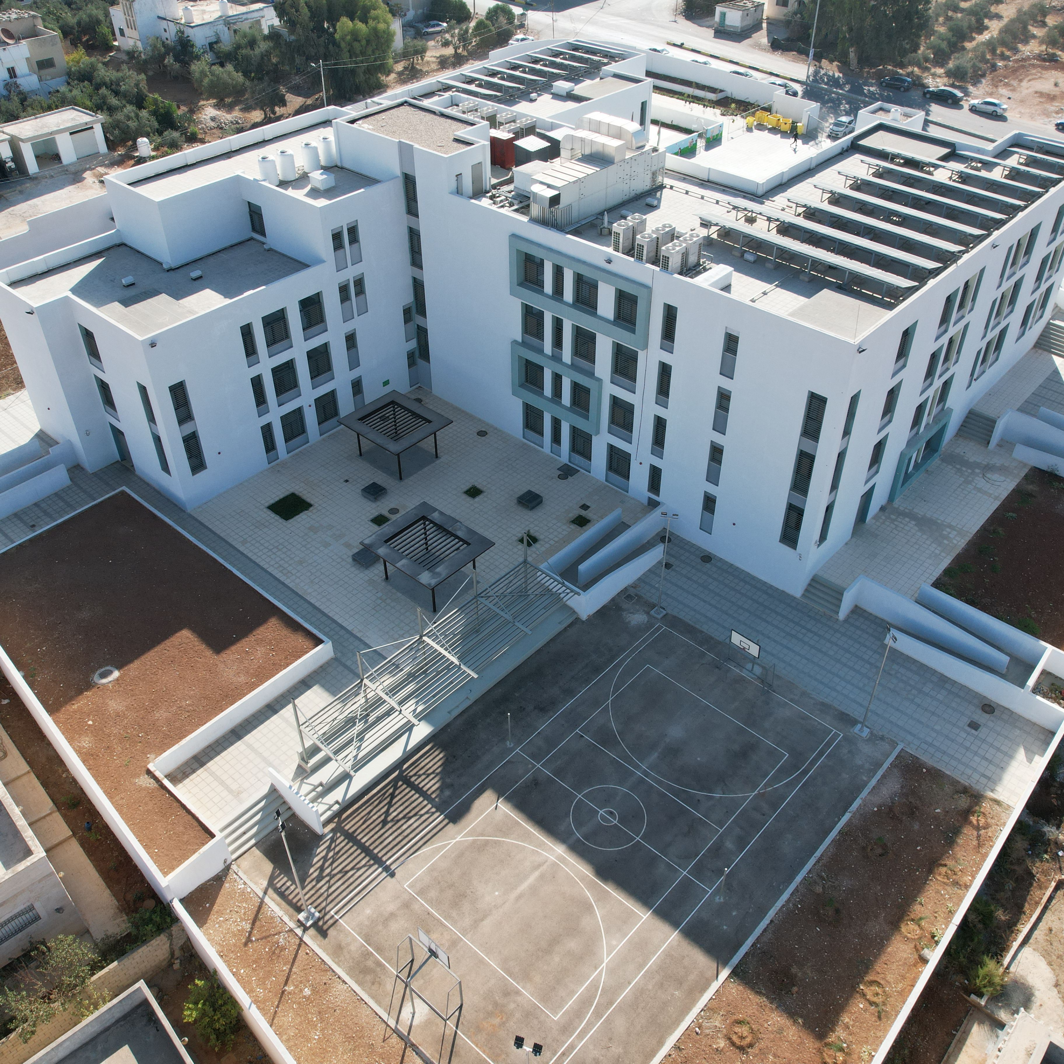 Bird view of modern school building with solar panels on the roof and external recreational areas.