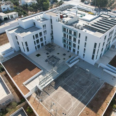 Bird view of modern school building with solar panels on the roof and external recreational areas.