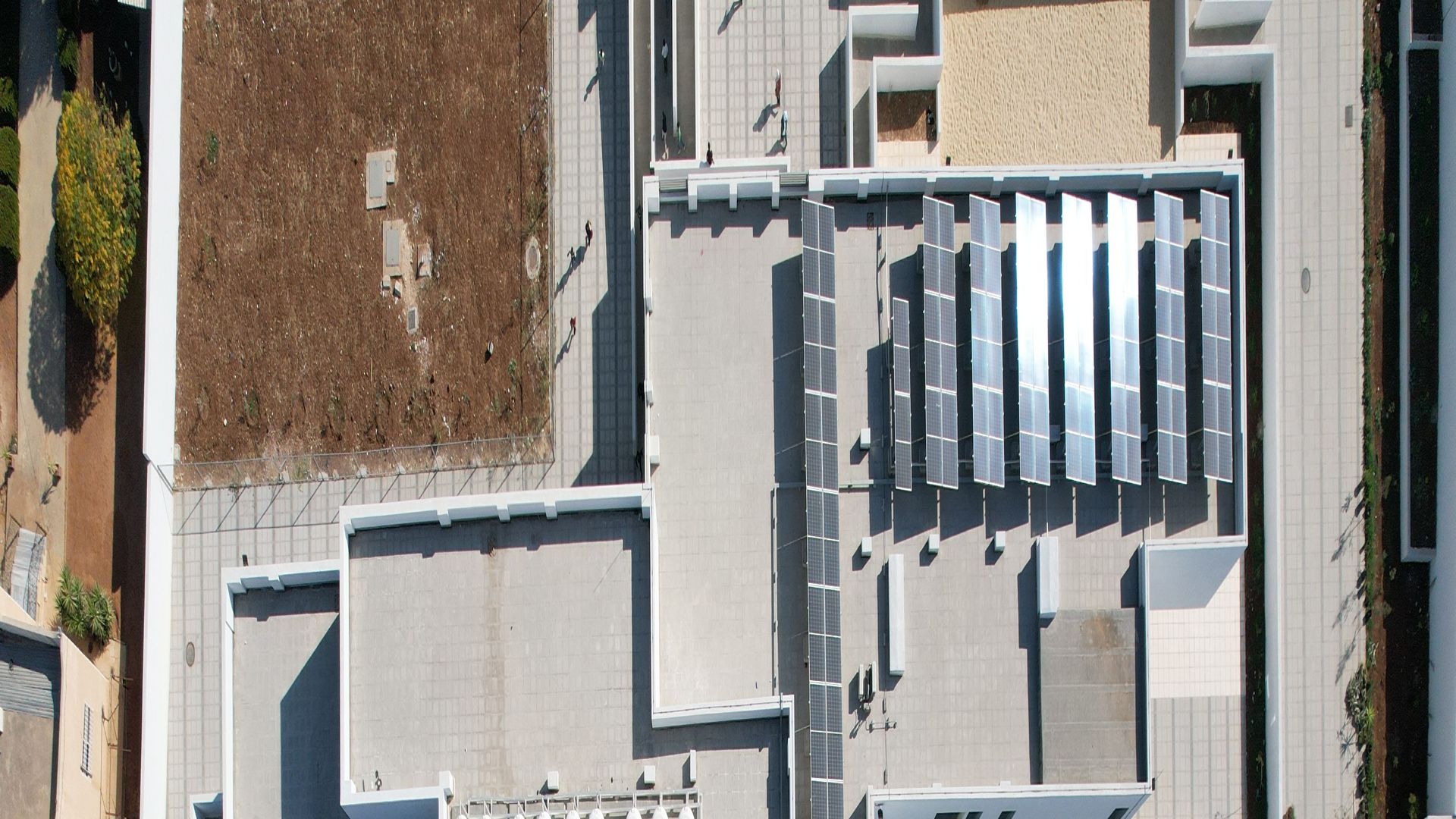 Bird view of a school building with solar panels on the roof and external recreational areas.
