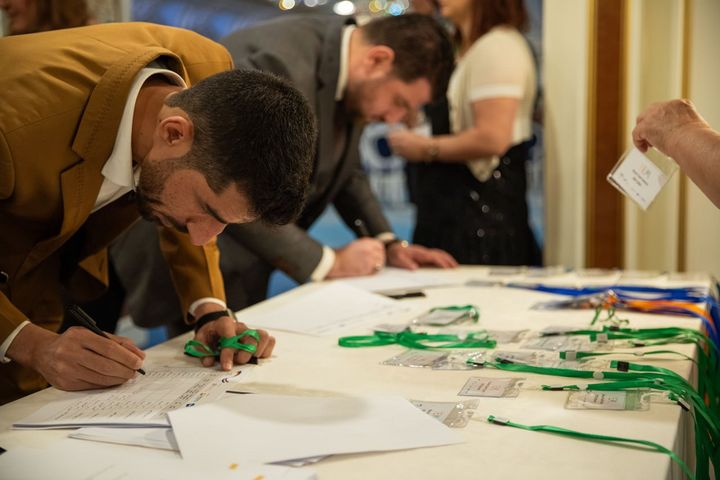 Two young men filling out forms on a desk during a job fair.