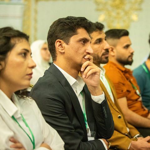 A row of young people sitting in the audience during a graduations ceremony.
