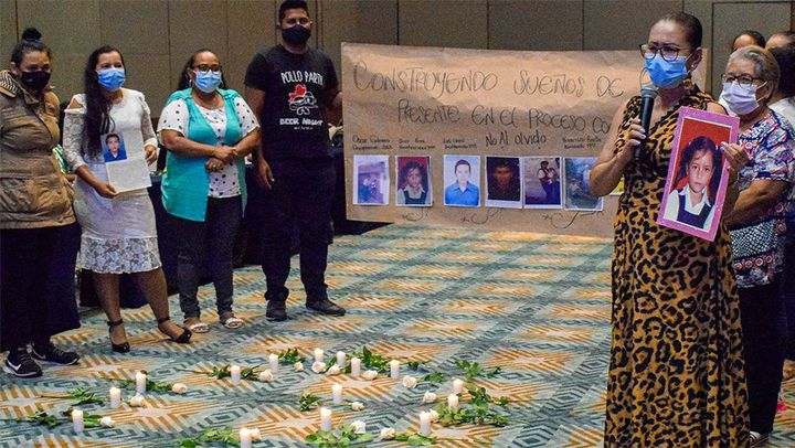 A group of people around litten candles holding pictures of people disappeared during the armed conflict in Colombia.