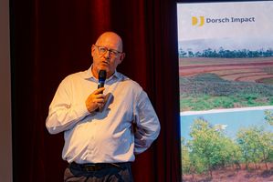 A man with a microphone in his hand standing on a small stage next to a banner.