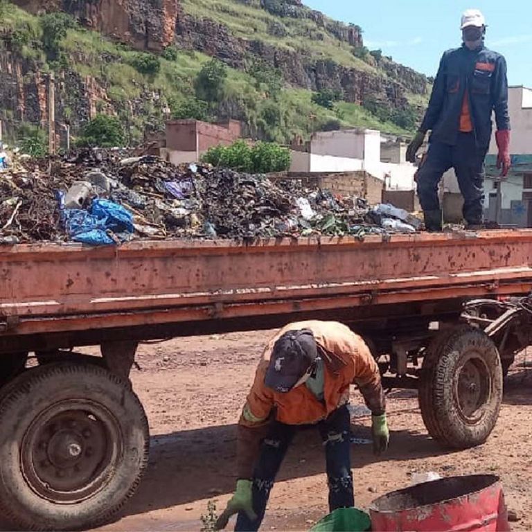 Waste collectors with trailer and tractor working on the street.