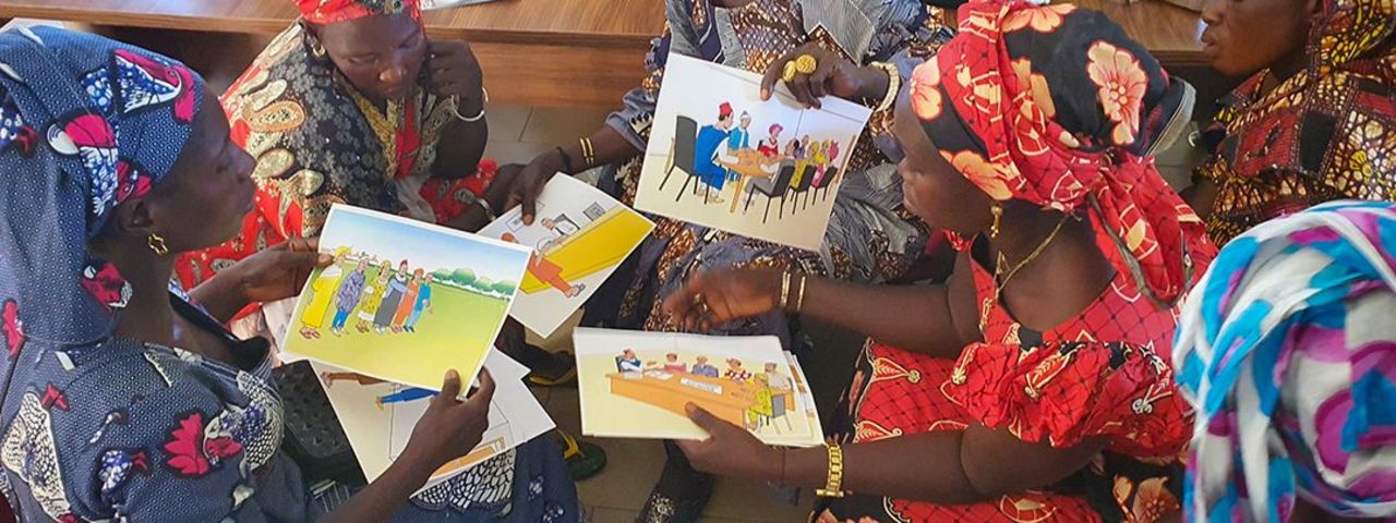 A group of Senegalese women discussing informational material on land rights. 