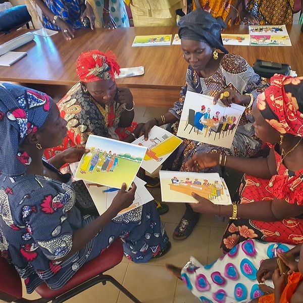 A group of Senegalese women discussing informational material on land rights 