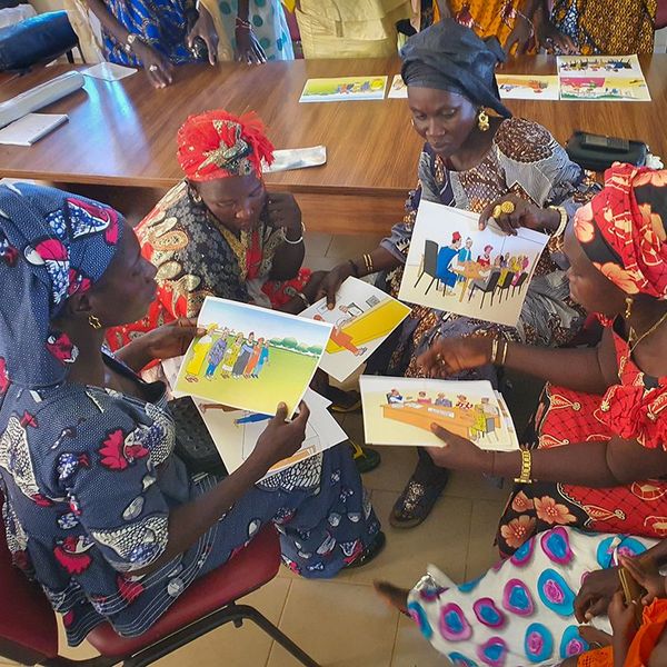 A group of Senegalese women discussing informational material on land rights 