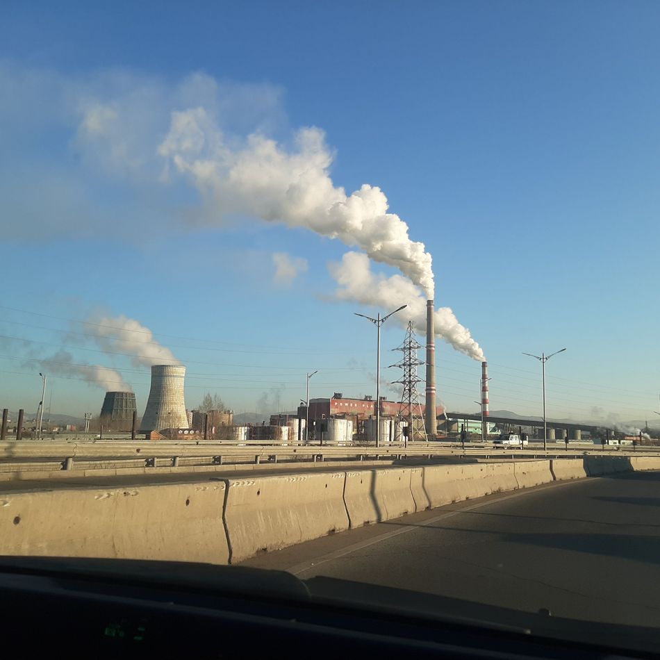 Smoking chimneys in a concrete landscape under a blue sky.