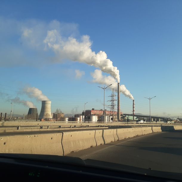 Smoking chimneys in a concrete landscape under a blue sky.