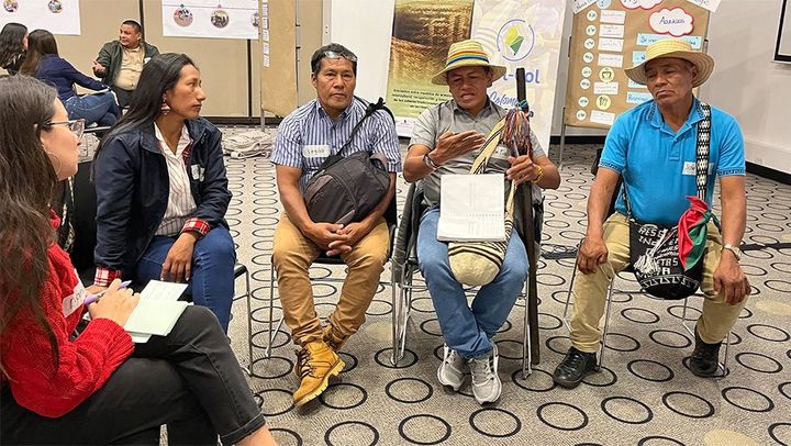 Three members of a local indigenous community sitting on chairs in an activity of the Col-Col conference for the ProPaz II project in Colombia.