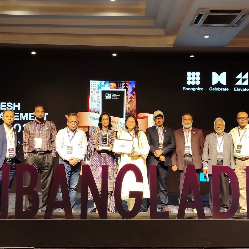 The delegation of the CReLIC team with the PM Award and diploma behind a big board saying #pmibangladesh 